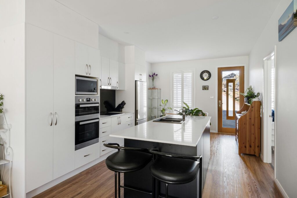 A sleek contemporary kitchen featuring a modern island, white cabinets, and wooden flooring.