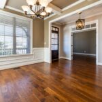 Elegant room with wooden flooring, chandelier, and natural lighting.