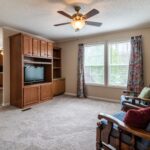 Spacious living room with classic wooden entertainment center and ceiling fan, perfect for a family setting.