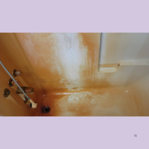 Orange bathtub with peeling enamel and rust stains around the drain and fixtures, showing age and wear.