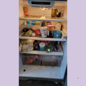 Open refrigerator with a cluttered interior: jars, cartons, tubs, and assorted groceries strewn across shelves and a messy bottom drawer edge visible below the shelves.