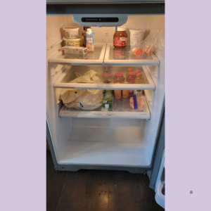 Open refrigerator with various condiments, drinks, and groceries on shelves; bottom drawer empty.