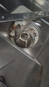 Close-up of a rusted central hub and white plastic supports inside a stainless steel appliance, likely a blender/mixer attachment.